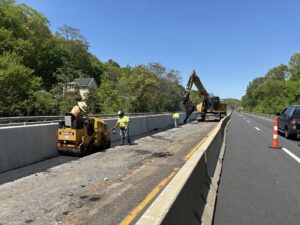 Workers paving after new median barrier installation.