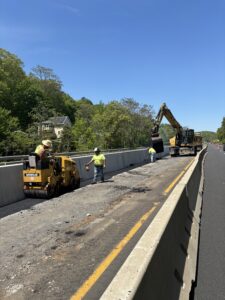 Workers paving after new median barrier installation.