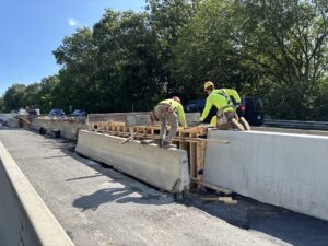 Workers install form for casting of new concrete barrier in the median work zone