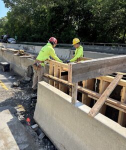 Workers install form for new concrete barrier