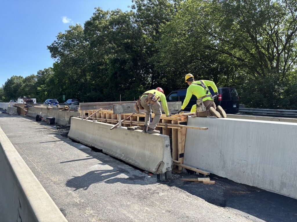 Workers install form for new concrete barrier