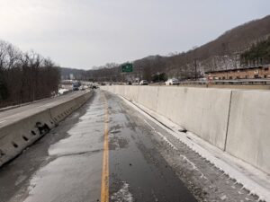 Permanent concrete median barrier with wet and snowy conditions in the work zone bordered with temporary concrete barrier and Route 8 traffic flowing normally