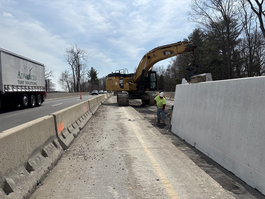 Worker prepares for installation of a precast concrete section of median barrier within the work zone.